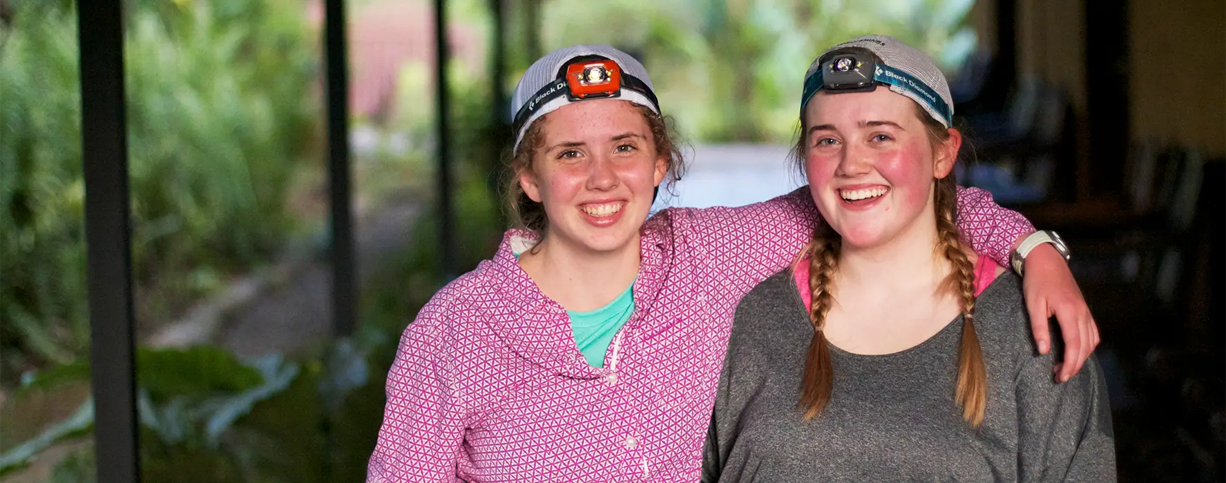 Two students wearing headlamps pose for a photo together.